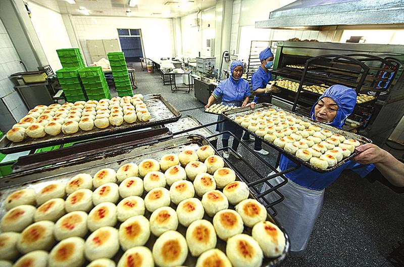 4月15日,德懋恭传统糕点生产车间,工人们正在将烤好的水晶饼拿出烤炉.