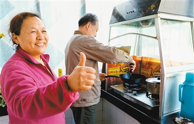 图为正在用天然气做饭的杜师傅夫妇 (记者 郝钟毓 摄)