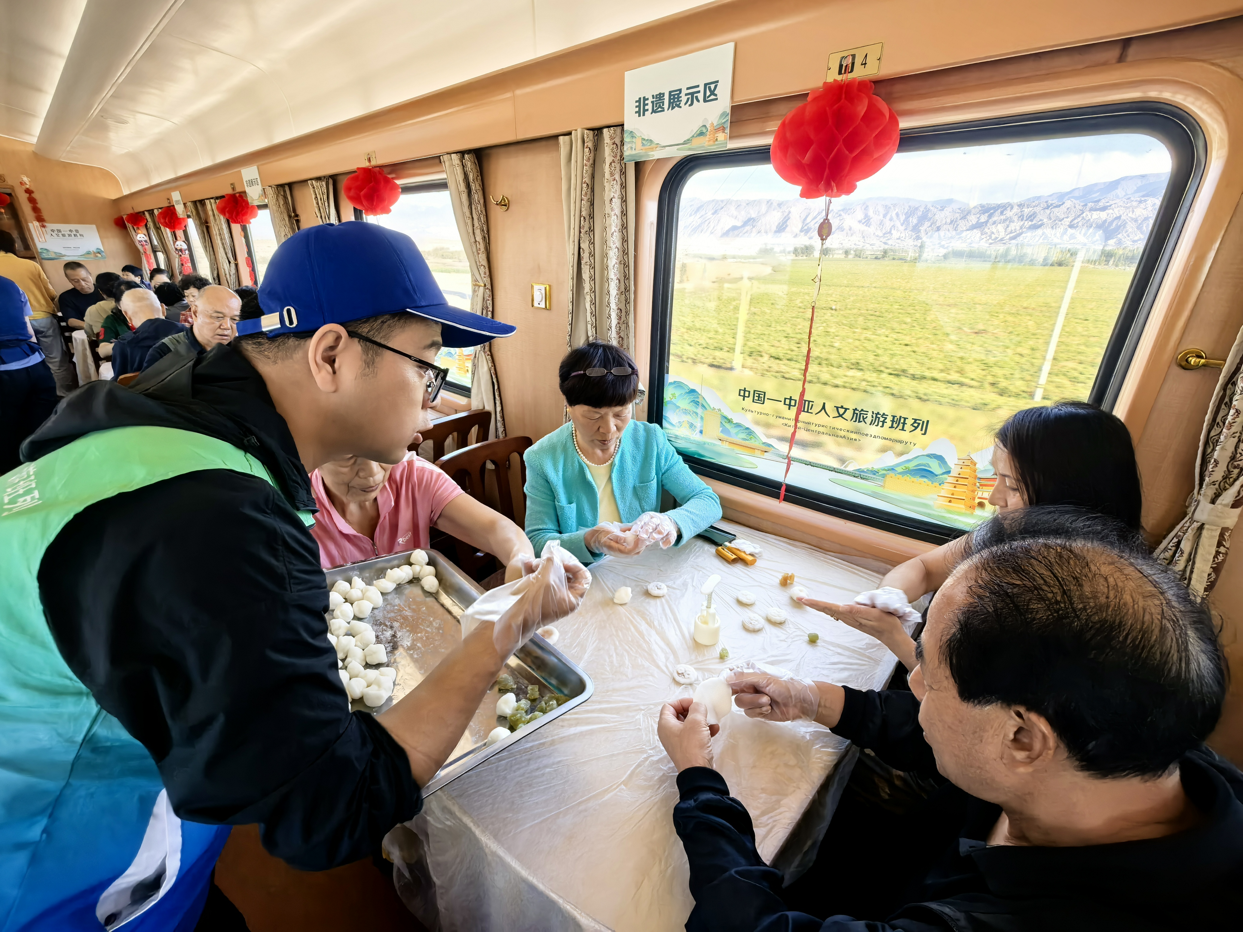 9月24日,在2026年第二趟中国——中亚人文旅游班列上,工作人员为旅客精心准备了一场别开生面的中秋主题体验活动。图为西安海外旅游有限责任公司工作人员现场耐心讲解冰皮月饼的制作步骤,手把手指导旅客揉团、压皮、包馅、收口、压模成型。