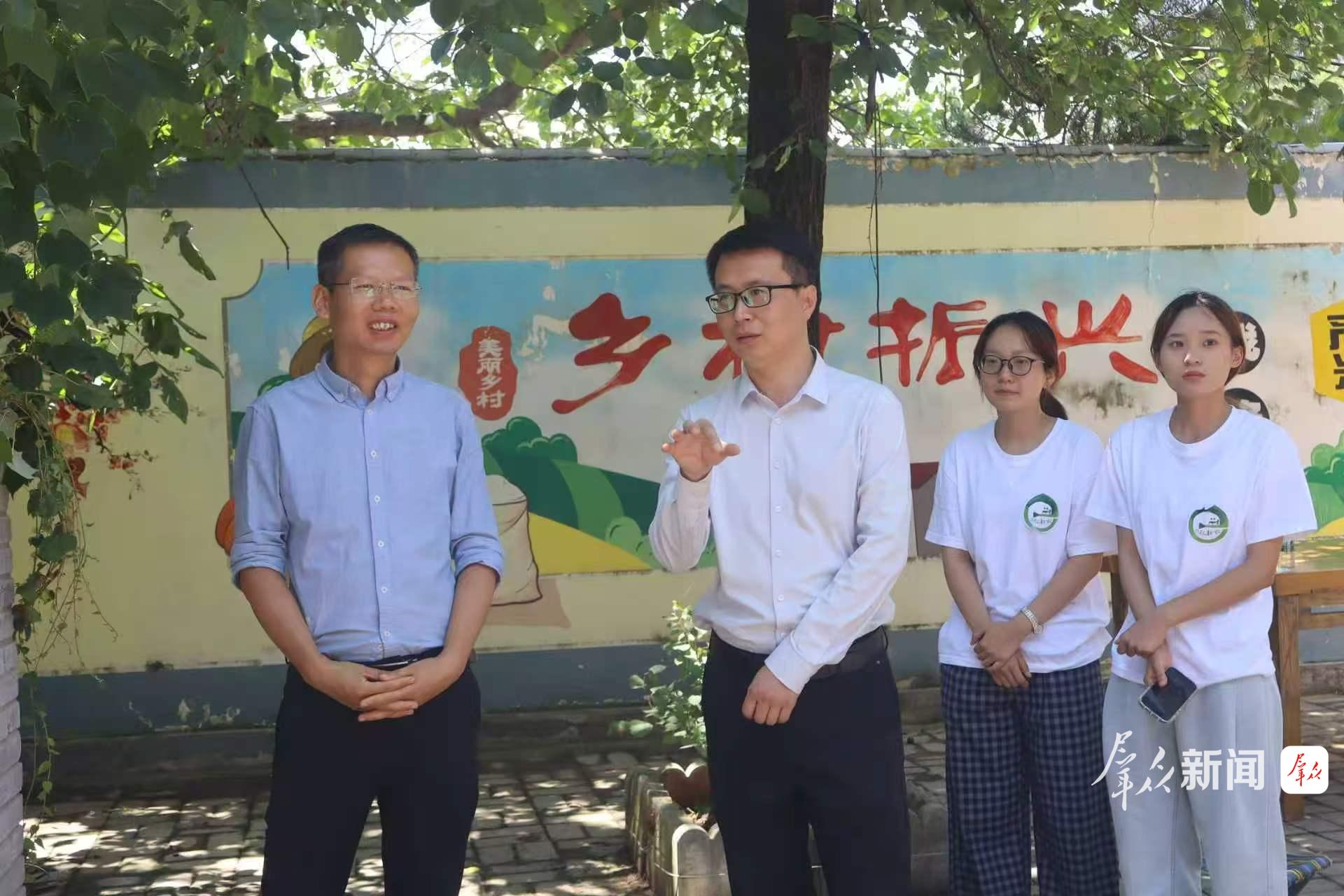 姜兴健(左二)与同事交流驻村工作经验。