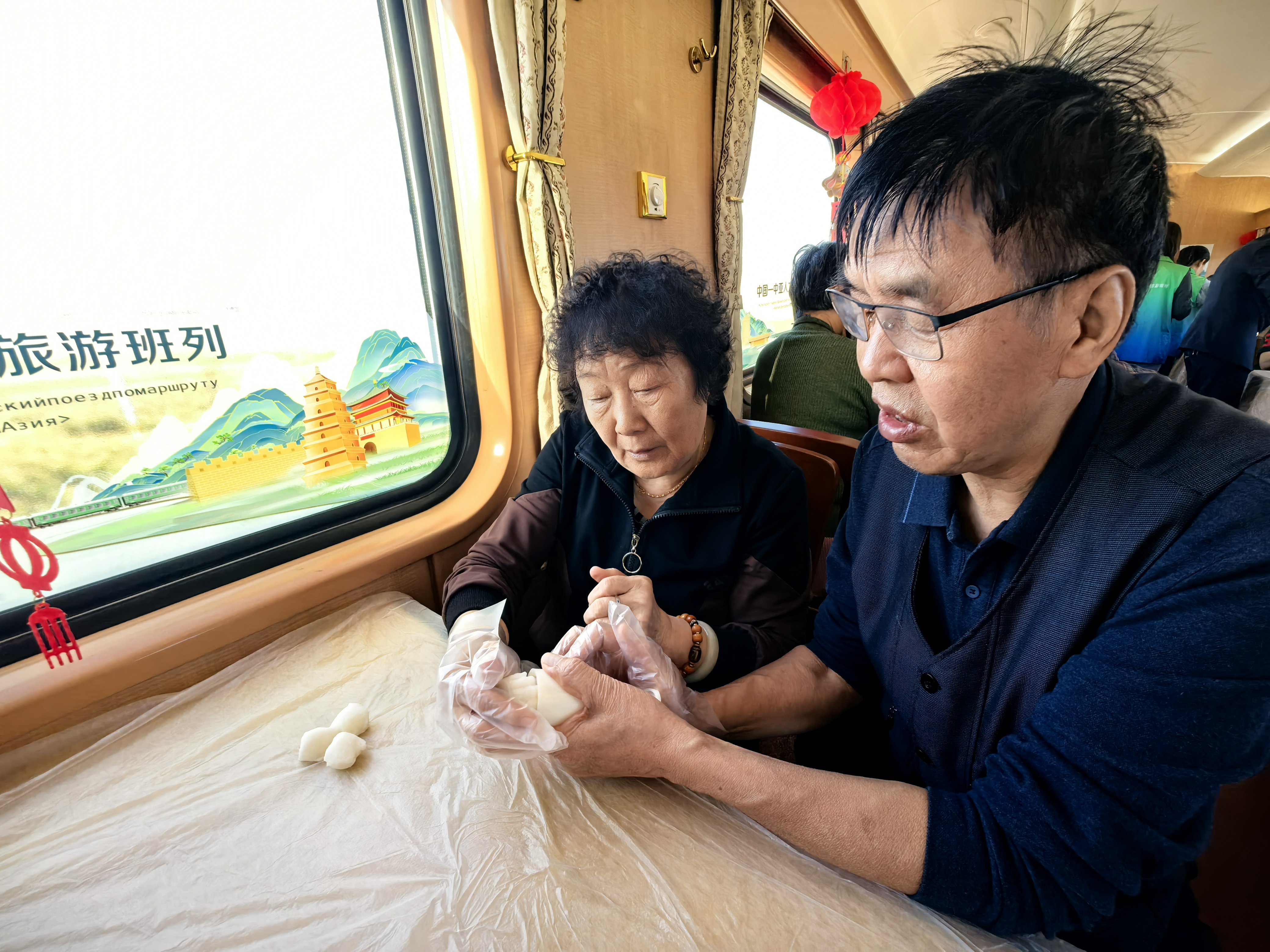 9月24日,在2026年第二趟中国——中亚人文旅游班列上,工作人员为旅客精心准备了一场别开生面的中秋主题体验活动。图为乘客亲手制作冰皮月饼。