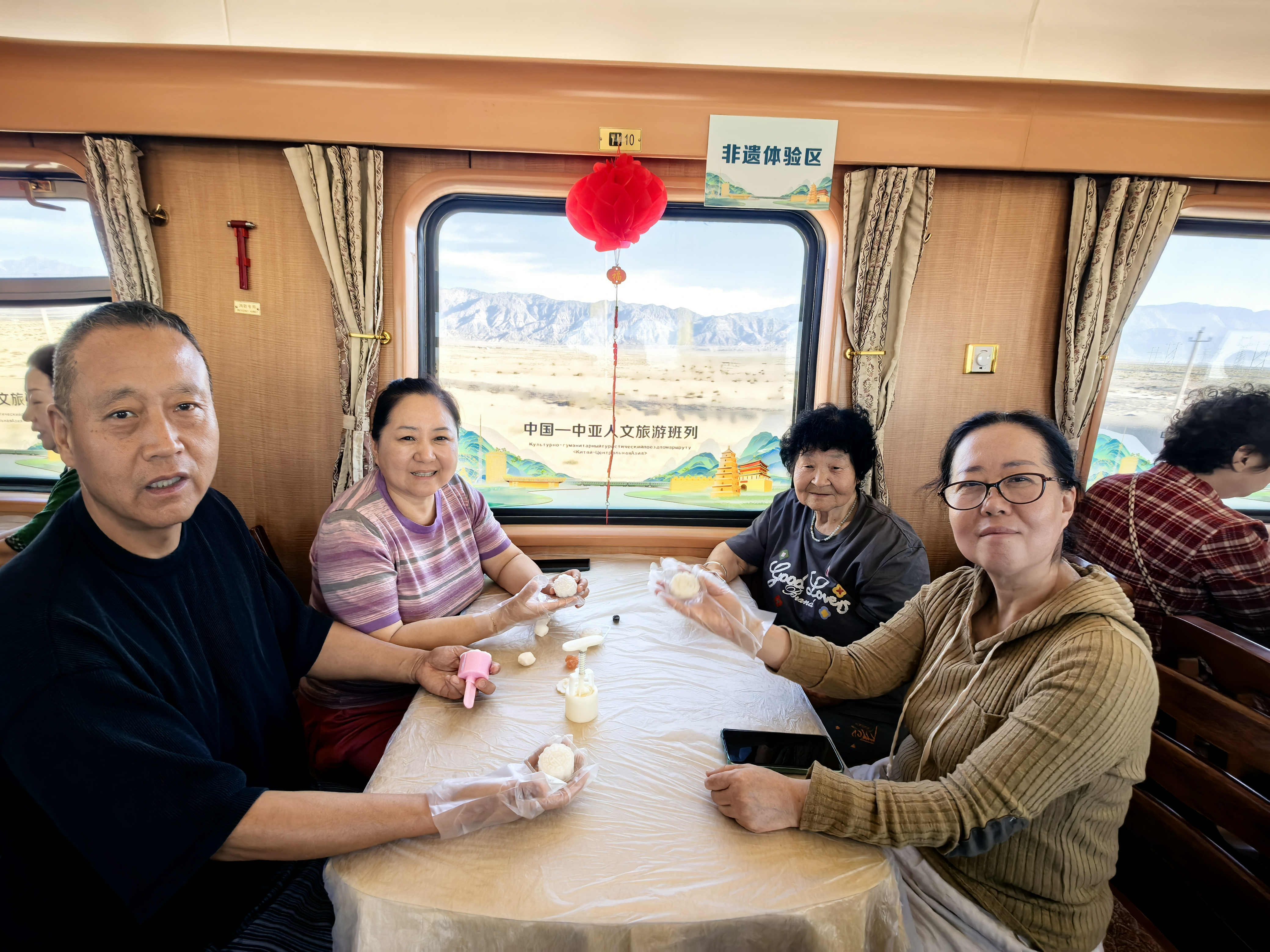 9月24日,在2026年第二趟中国——中亚人文旅游班列上,工作人员为旅客精心准备了一场别开生面的中秋主题体验活动。图为乘客展示刚制作好的冰皮月饼。