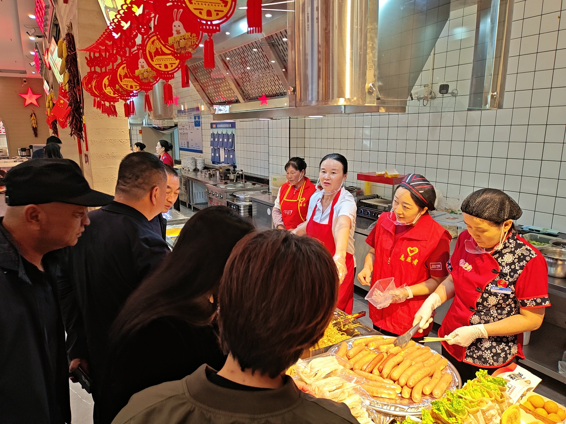 10月1日,在包茂高速延安西服务区,志愿者协助餐厅工作人员给司乘人员打饭。 群众新闻记者 霍海澎摄